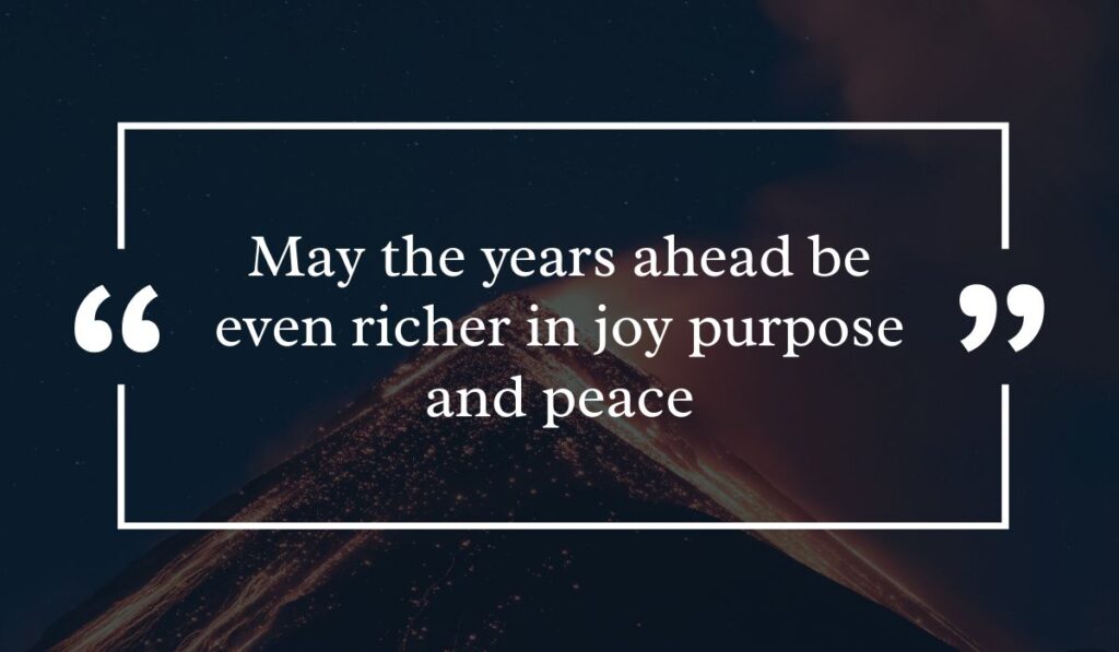 Dramatic dark night sky background featuring a lit volcanic peak at night, centered with a white quotation box highlighting encouraging happy birthday wishes for 50th birthday: "May the years ahead be even richer in joy purpose and peace".