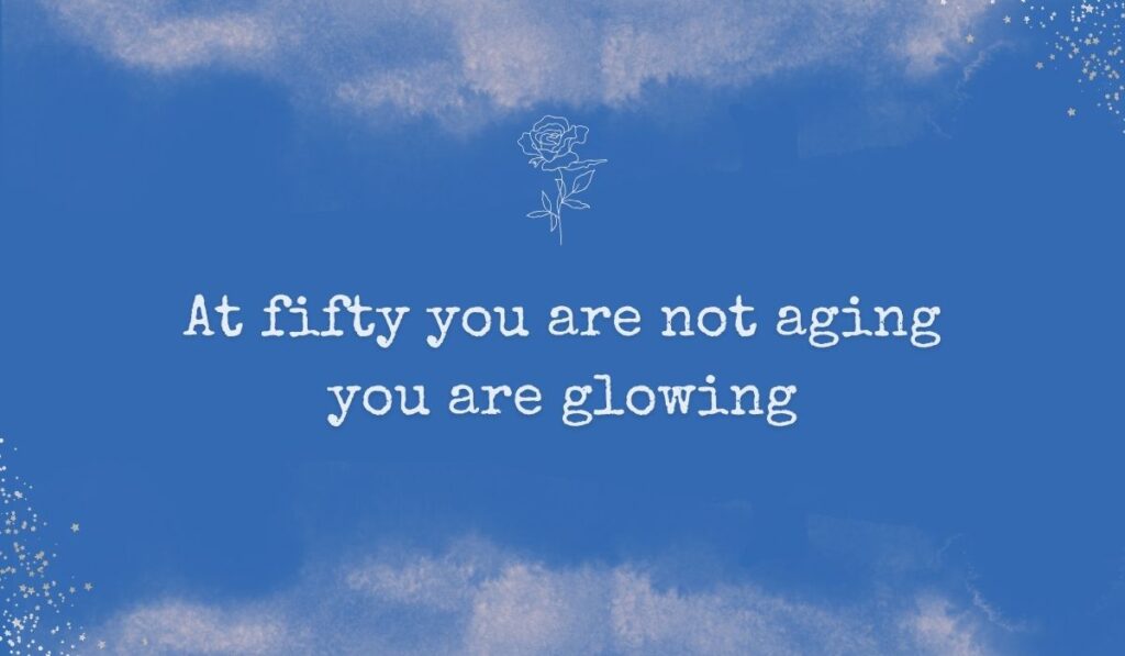 Rich royal blue watercolor background with subtle stardust detailing in the corners and a fine white line-art rose centered at the top, framing complimentary quotes for 50th birthday for woman: "At fifty you are not aging you are glowing".