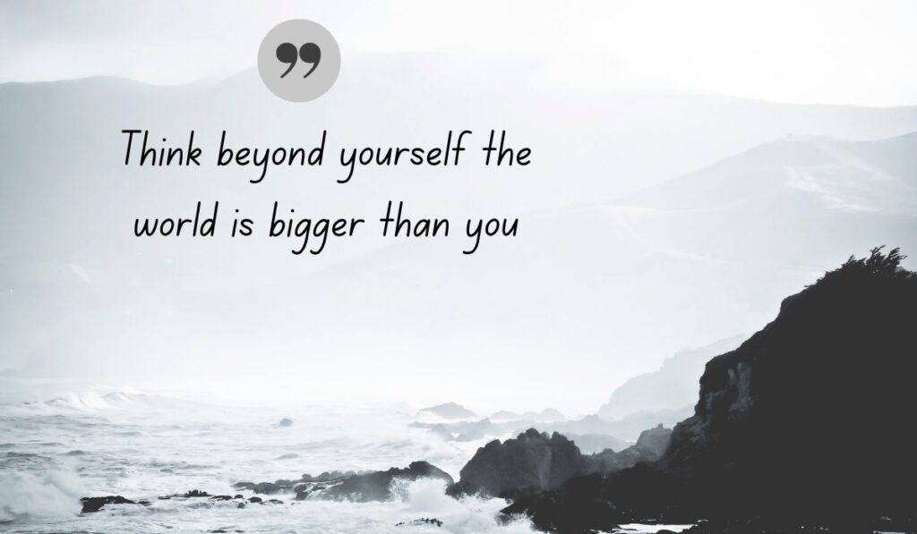 Atmospheric black and white coastal photograph of crashing ocean waves against rugged cliffs, centered with a dark gray quotation icon framing strong quotes for people who are selfish: "Think beyond yourself the world is bigger than you".