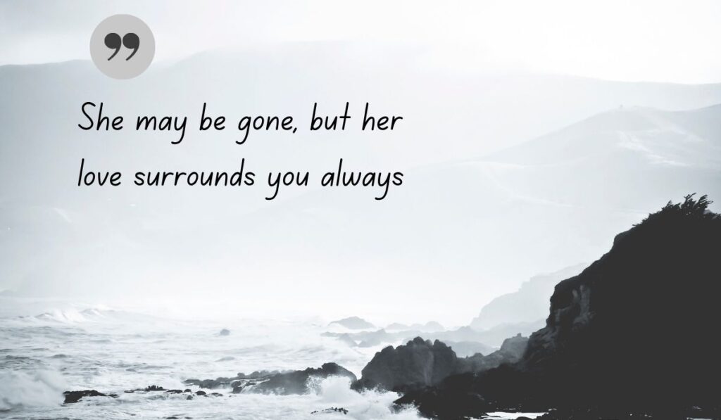 Atmospheric black and white coastal image of crashing ocean waves against rocky cliffs, centered with a dark gray quotation icon framing the handwritten comforting text, "She may be gone, but her love surrounds you always".